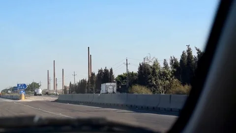 Passenger looking through the front driving car on a high way to a factory Stock Footage 80010814