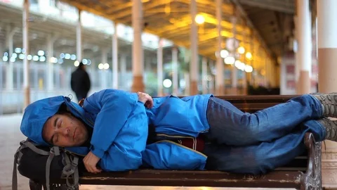 Passenger man sleeping on bench at train station Stock Footage 100608141