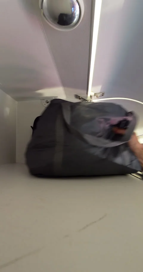 Passenger pick up soft bag and laptop case bag from overhead compartment Stock Footage 297053714