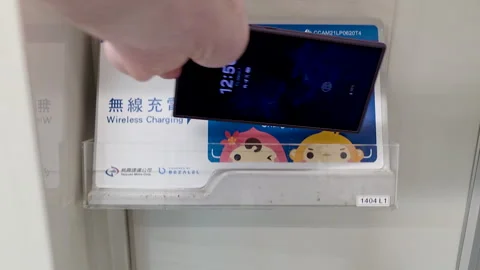 Passenger placing smartphone in onboard wireless charger on Airport MRT train Vidéo 334228062