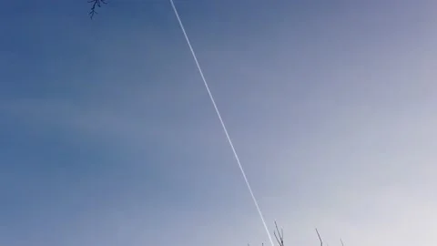 A passenger plane flies high in the sky and leaves a smoke trail behind it. Video stock 169494543