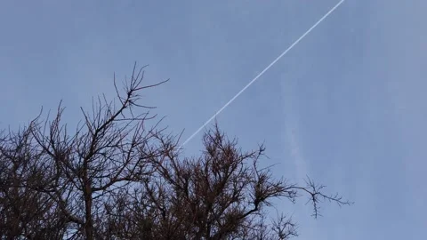A passenger plane flies high in the sky and leaves a smoke trail behind it. Stock-Footage 169494557