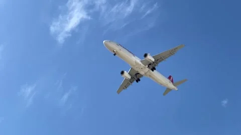 Passenger plane flies low over and slow against blue sky Stock Footage 305237518