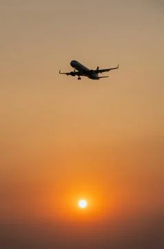 Passenger plane is landing on the background of the setting sun Stock Photos