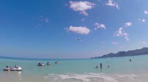 Passenger plane passes low overhead tourists on the beach. Stock Footage 51126336