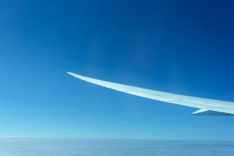 Passenger plane wing stretching into blue sky Stock Photos