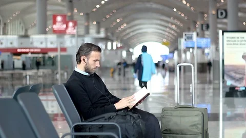 Passenger reading a book at departure lounge at the airport Stock Footage 99066986