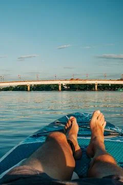 Passenger relaxing barefoot on a paddleboard while floating on a calm tropical Stock Photos