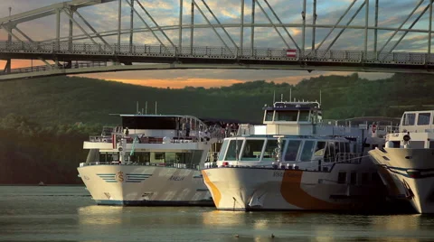 Passenger ship docking on the river under the bridge in the sunset Stock Footage 67656420