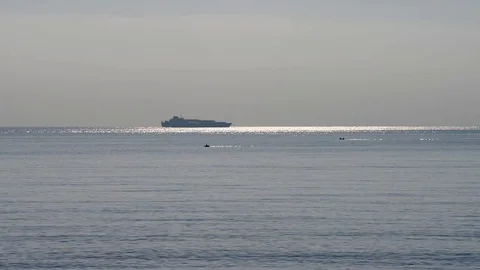 Passenger ship sails on the horizon over the calm and shimmering sea Stock Footage 83536092
