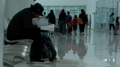 Passenger siting, waiting for his flight schedule by reading a book Stock Footage 122603084