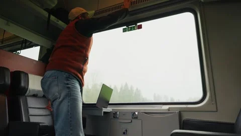 A Passenger Sits by the Train Window, Waving His Hand to Cool Himself While Stock Footage 333795734