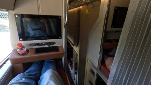 A passenger in sleeper bus, upper bunk with TV. Legs. Street view from a window Stock Footage 248679261