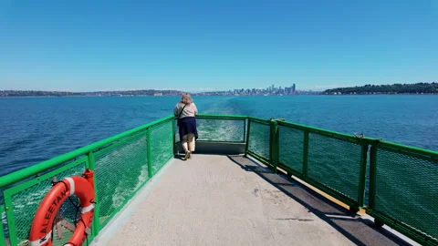 Passenger stand on the open deck of a Seattle ferry. Green railings and bright Stock Footage 320580649