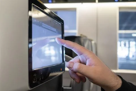 A passenger touches a multimedia touchscreen on a train to represent modern.. Stock Photos