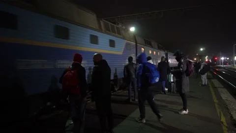  a passenger train arrives at the station at night. passengers on the platform Stockbeeldmateriaal 143871682