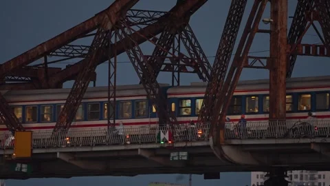 Passenger train crossing historic Long Bien Bridge in Hanoi, Vietnam at dusk Stockbeeldmateriaal 344743061