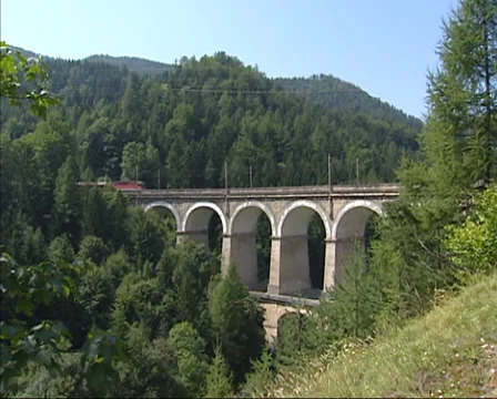 Passenger train crossing Kalte Rinne viaduct + pan excavated rocks and debris Stock Footage 33538093