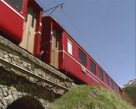 Passenger train direction St.Moritz approaching + crossing viaduct - low angle Stock Footage 43826395