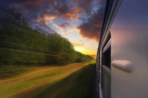 Passenger train in motion with blur effect in the forest at sunset. Stock Photos