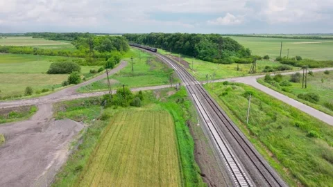 Passenger train moves along rural railway passing railway crossing aerial view Stock Footage 319953072