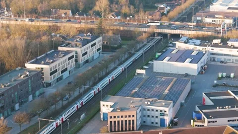Passenger train moves parallel railway tracks amid modern offices solar panel Video stock 329087131