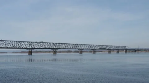 Passenger train rides on a railway bridge over a wide river on a spring day Stockbeeldmateriaal 127496898
