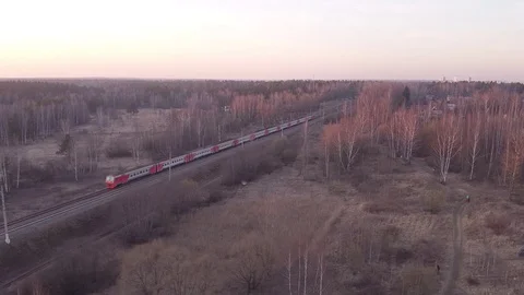 A passenger train rides through a spring forest at sunset. quadrotor filming Stock Footage 128924696