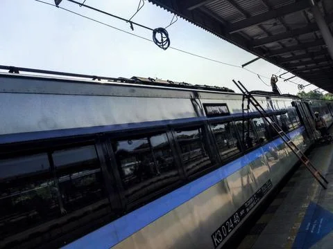 Passenger train stopped at station platform under open roof Stock Photos