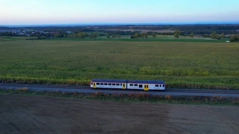 A passenger train travels by rail between agricultural fields. Top view from the Stock Footage 167672235