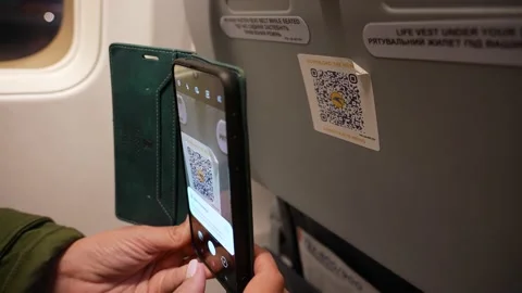 Passenger using smartphone to scan QR code on back of seat in plane Stock Footage 191063465
