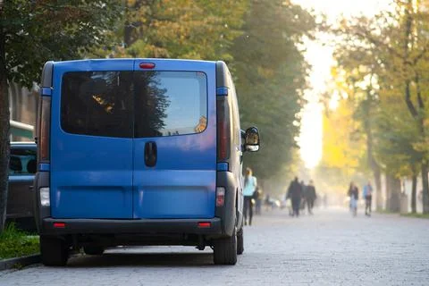 Passenger van car parked on a city alley street side with blurred walking ped Stock Photos