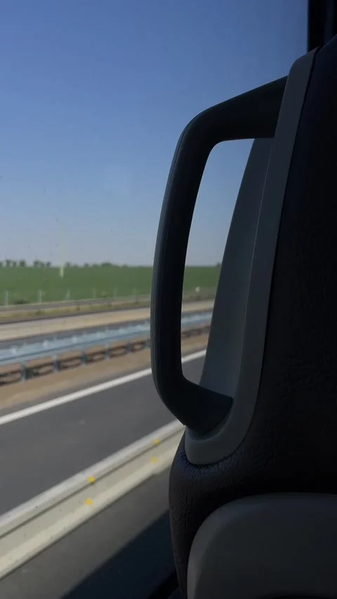 Passenger view of grab handle and headrest beside highway with fields outside Видео 341662997