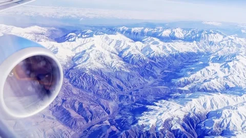 Passenger view over snow covered alpine mountains from airplane window with Stock Footage 345437460