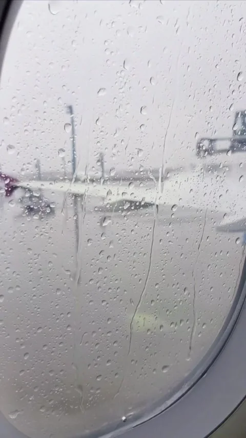 Passenger view through aircraft window as ground crew performs aircraft deicing  Stock Footage 336960499