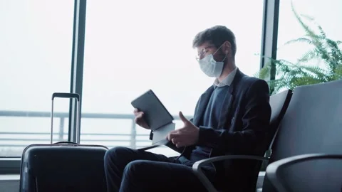 Passenger wearing a protective mask using his tablet in the airport lounge. Stock Footage 221121366
