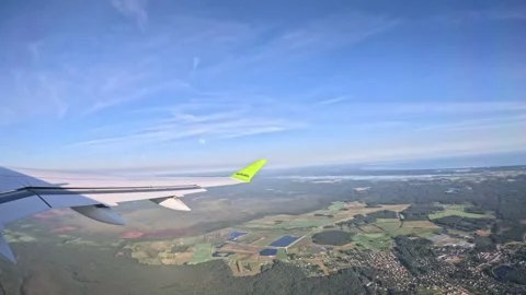 Passenger window view of aircraft climbing above green landscape near sea coast Stock Footage 340320557