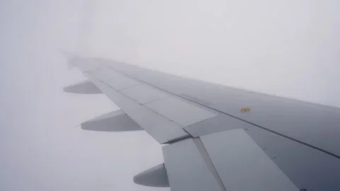 Passenger-window view of an airplane wing disappearing into dense fog Stockbeeldmateriaal 334535694