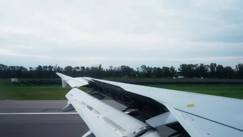Passenger window view of a jet wing rolling on the runway after landing, with Vidéo 336224278