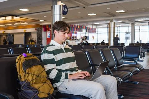 Passenger working on his laptop while waiting in the departure lounge. Stock Photos