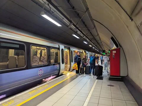 Passengers and Elizabeth Line train at busy Heathrow Airport station platform Fotos de archivo