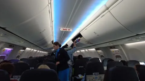 Passengers and flight attendant preparing for departure Stock Footage 202242306