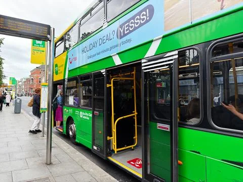 Passengers boarding a green double decker bus at a busy city stop in Dublin.. Stock-Fotos