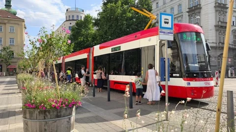 Passengers boarding a modern red tram at a city stop 库存影片 341894932