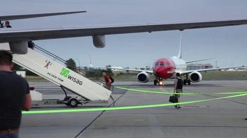 Passengers boarding a plane while another aircraft is arriving at the runway Stock Footage 71445274