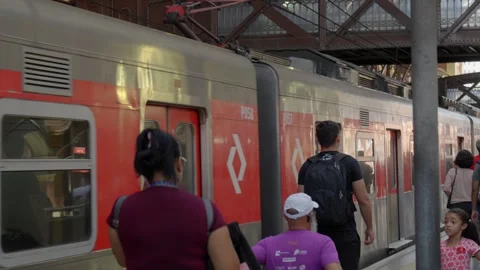 Passengers boarding a red and silver commuter train at a busy railway station p Stock-Footage 338185641