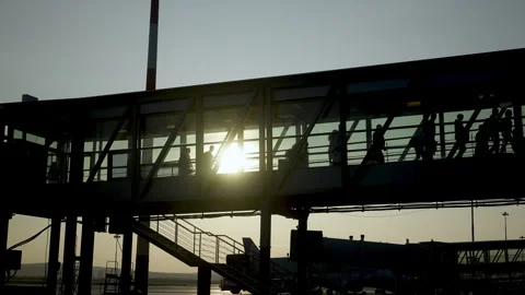 Passengers boarding using an air bridge. People walk in silhouette along ramp Stock Footage 255247435