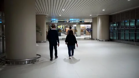 Passengers carrying suitcases walk along a terminal corridor inside Stock Footage 344689448