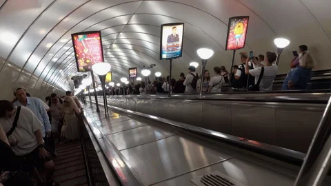 Passengers descend a long, deep Saint Petersburg metro escalator into a cro.. Stock Footage 323972775