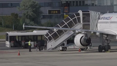 Passengers disembark plane using boarding stairs then board airport bus Stock Footage 119830693